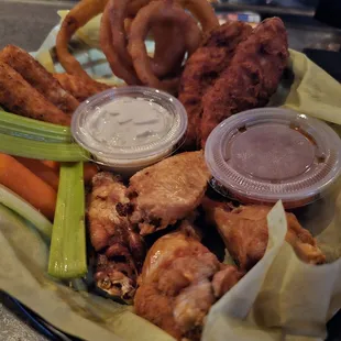 a plate of chicken wings, carrots, celery, and onion rings