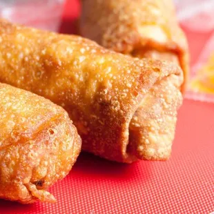 two fried spring rolls on a red cutting board