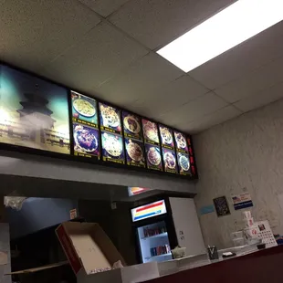a restaurant counter with menus on the wall