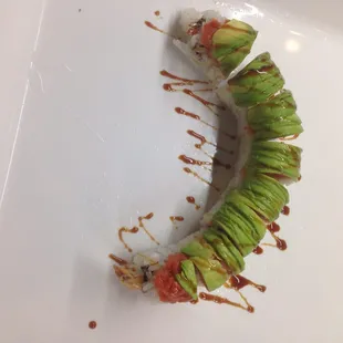 a sushi roll with avocado and sauce