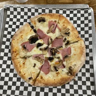 a pizza with ham, mushrooms, and cheese