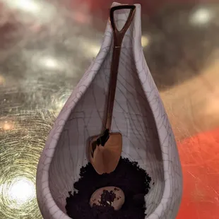 a spoon with dirt and a shovel in it