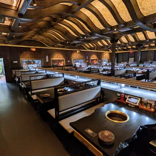 Inside. Dining room. There are three conveyor belts, each surrounded on either side by five booths. Some booths seat four, others six.