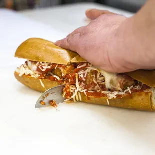 a person cutting a sub sandwich