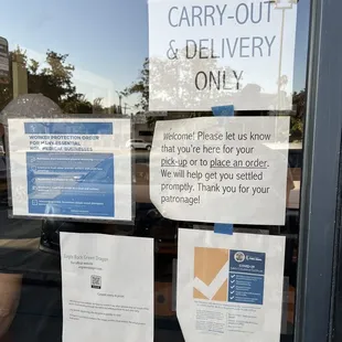 a sign in the window of a carry out and delivery only store