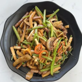 a black bowl of stir fried vegetables