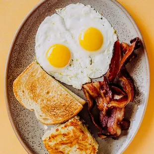 a breakfast plate with toast, eggs, bacon and toast