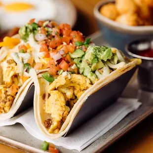 two tacos on a tray with a side of fried eggs