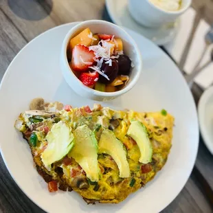 Three Egg Omelet with avocado, jalapeños, tomatoes, onions, and mushrooms. Side of fruit and grits.