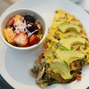 Three Egg Omelet with avocado, jalapeños, tomatoes, onions, and mushrooms. Side of fruit.