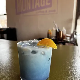 a blue drink with a lemon wedge