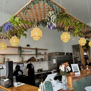 a restaurant counter with plants hanging from the ceiling