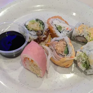 Six different pieces of sushi with a side of teriyaki sauce