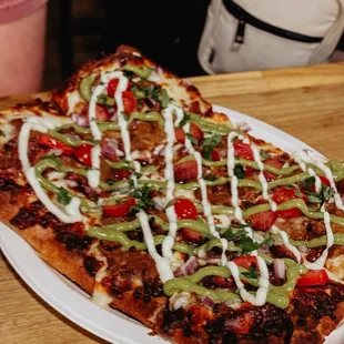 Sonoran Dog pizza, with  garlic oil, refried beans, mozzarella, hotdog, bacon, tomato, onion, guacamole , mayo, and cilantro .