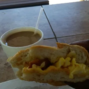 Cafe con leche and half of a Bacon, egg and cheese breakfast sandwich.