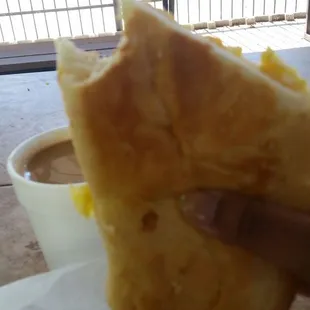 Cafe con leche and half of a Bacon, egg and cheese breakfast sandwich