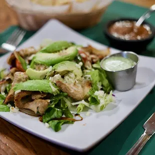 a plate of salad with chicken and avocado