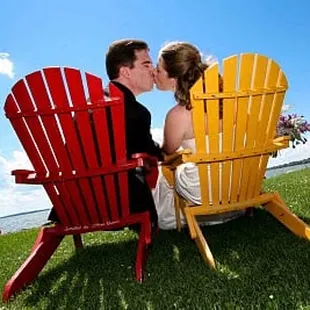 a bride and groom kissing on a lawn