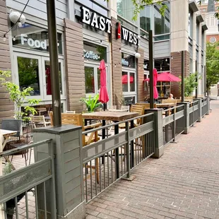 a sidewalk with tables and umbrellas