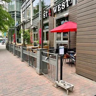 a sidewalk with tables and umbrellas
