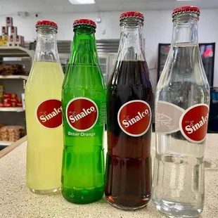 three bottles of soda and a glass of water