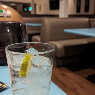a glass of water with ice and a slice of lemon