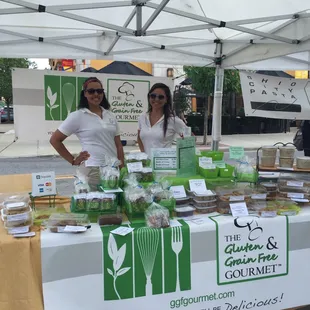 two women standing in front of a farmers market