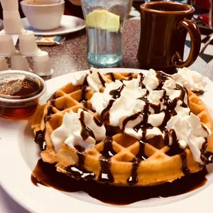 a waffle with whipped cream and chocolate syrup