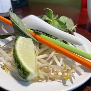 Garnishment: bean sprouts, Thail basils, and lime