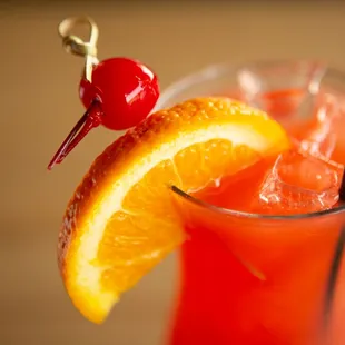 an orange drink with a cherry on top