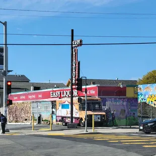 a man walking across the street in front of a liquor store