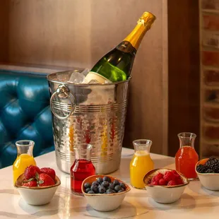 a bottle of champagne and bowls of fruit