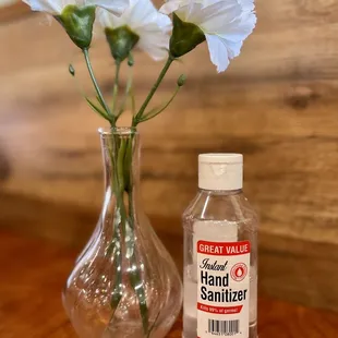 a bottle of hand sanitizer next to a vase of flowers