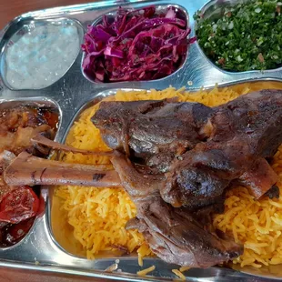 Lamb shank over yellow rice, with tzatziki, red cabbage, taboule, and eggplant.