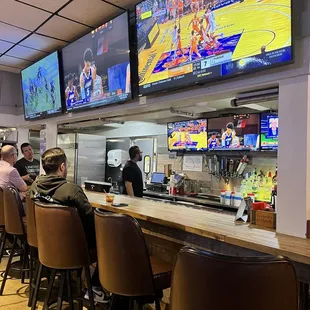 people sitting at the bar watching tvs