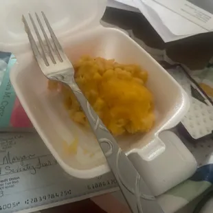 a fork and a container of macaroni and cheese