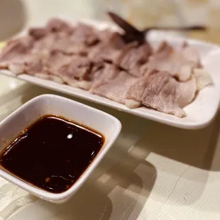 a plate of meat and a bowl of sauce