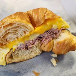 Half of a croissant sandwich with ham, egg, American cheese