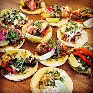 a variety of tacos on a wooden table