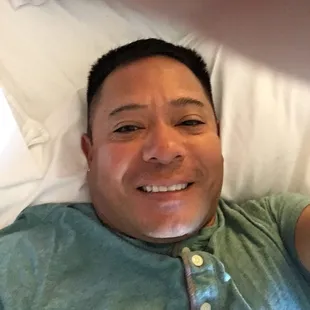 a man laying in a bed with a remote control in his hand