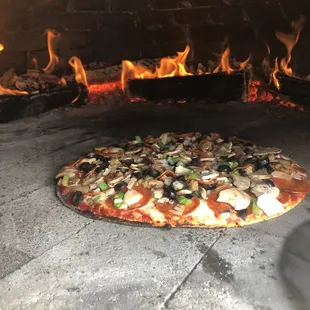 a pizza cooking in a brick oven