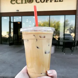 a hand holding a cup of iced coffee