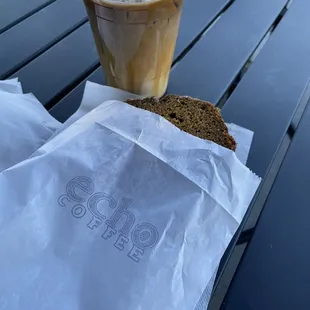 a sandwich and iced coffee on a picnic table