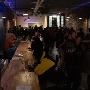 a group of people standing around a long bar