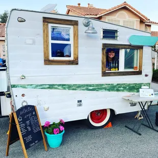 a woman looking out the window of a vintage camper