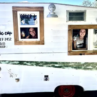a woman and a man looking out the window of a food truck