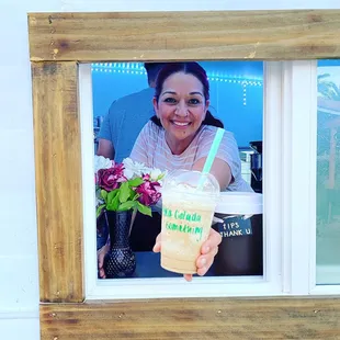a woman holding a drink in front of a window