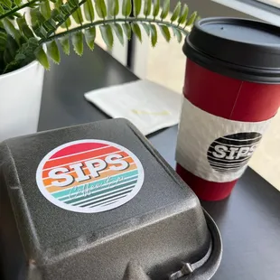 Morning bagel sandwich and cup of coffee. Sitting inside.