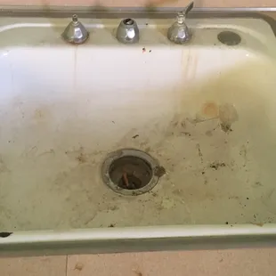 The bathroom sink I handles and a cigarette sitting inside of it