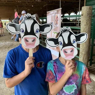 two children holding cow masks